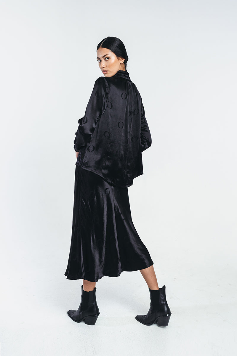 Black viscose shirt with o-logo, wrinkled turtle neck and buttoned sleeves worn by a model with matching o-logo skirt. Made from recycled viscose. Hálo from north