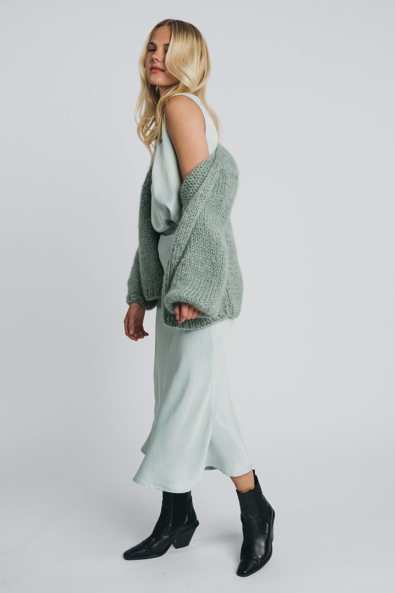 Huurre handkitted wrapknit in misty green worn with kajo slip skirt and loose top in misty green. Picture from the side. Hálo from north