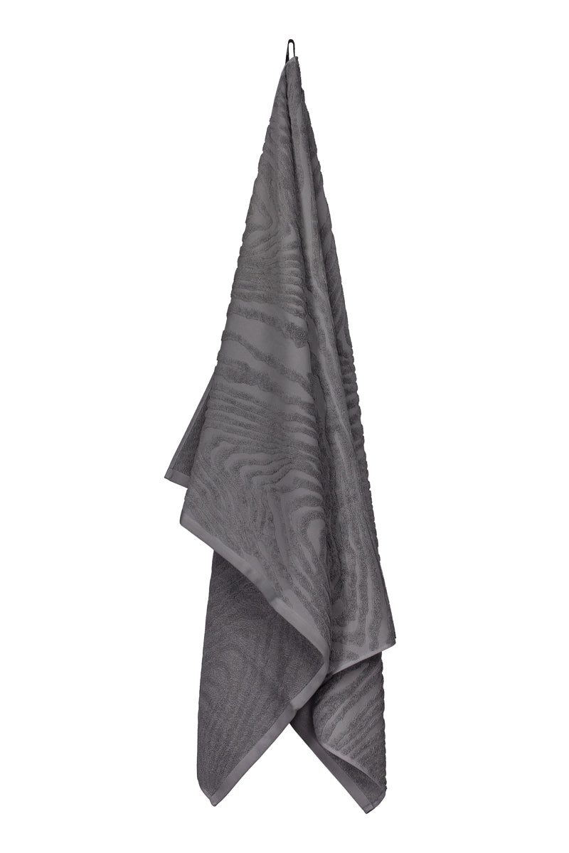 Kaarna bath towel in grey hanging from a hook. Hálo from north