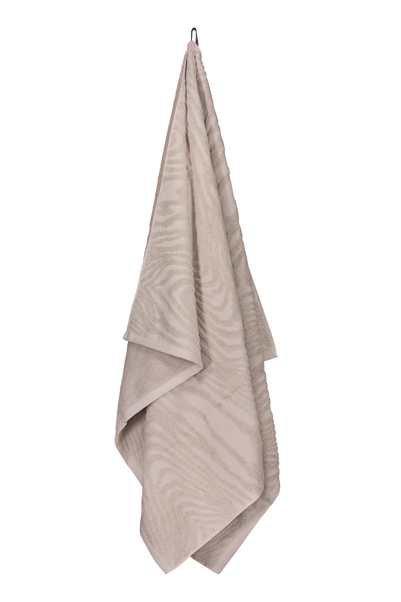 Kaarna bath towel in sand hanging from a hook. Hálo from north