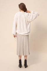 Tundra prairie blouse in natural white worn together with light colored slip skirt. Picture from behind. Hálo from north