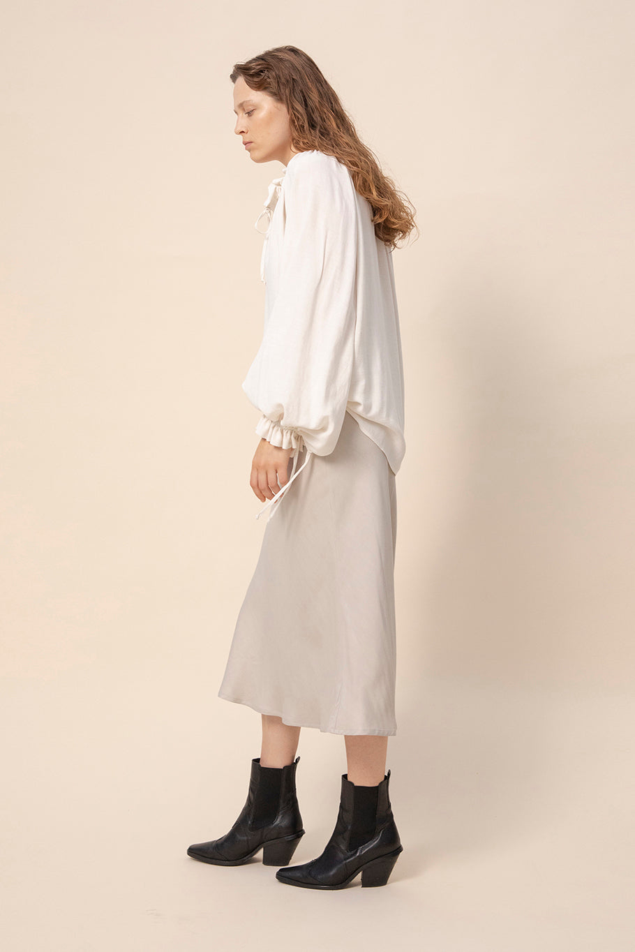 Tundra prairie blouse in natural white paired with light colored slip skirt. Sleeves tied to create a blouson sleeve. Hem tucked inside the skirt. Video. Hálo from north